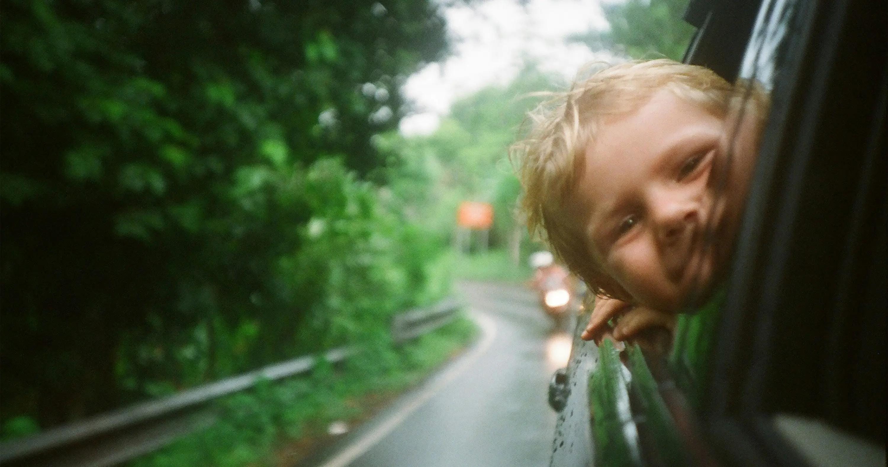 Niño en un auto, camino de ruta.